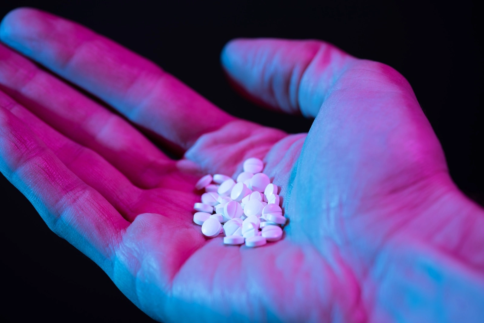 person holding a handful of white pills; can you overdose on ketamine