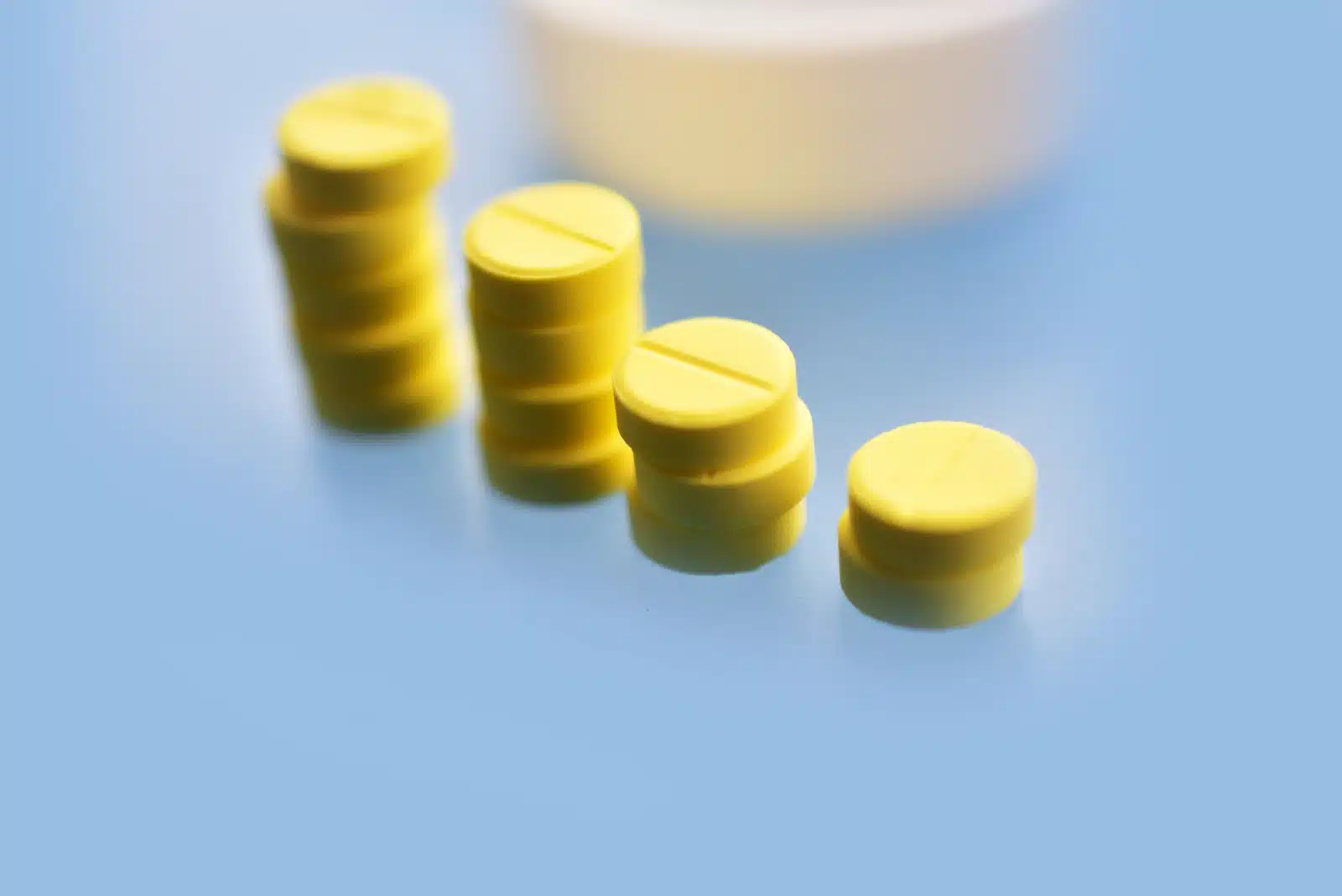 Can You Get a Meloxicam High? Yellow pills stacked in a row on a blue surface.