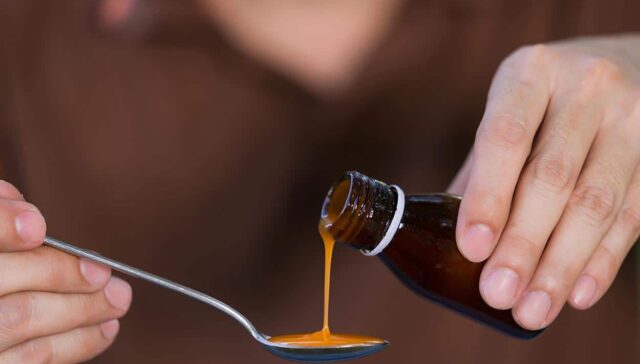 How Long Does NyQuil Stay In Your System? A person pouring cough medicine into a spoon.