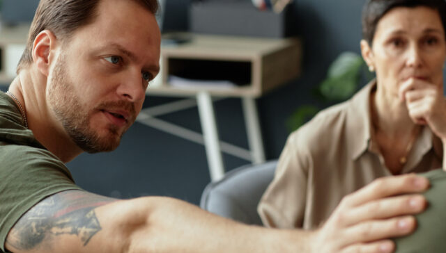 Therapist offering support to a person and veteran in trauma-informed treatment for PTSD and addiction recovery