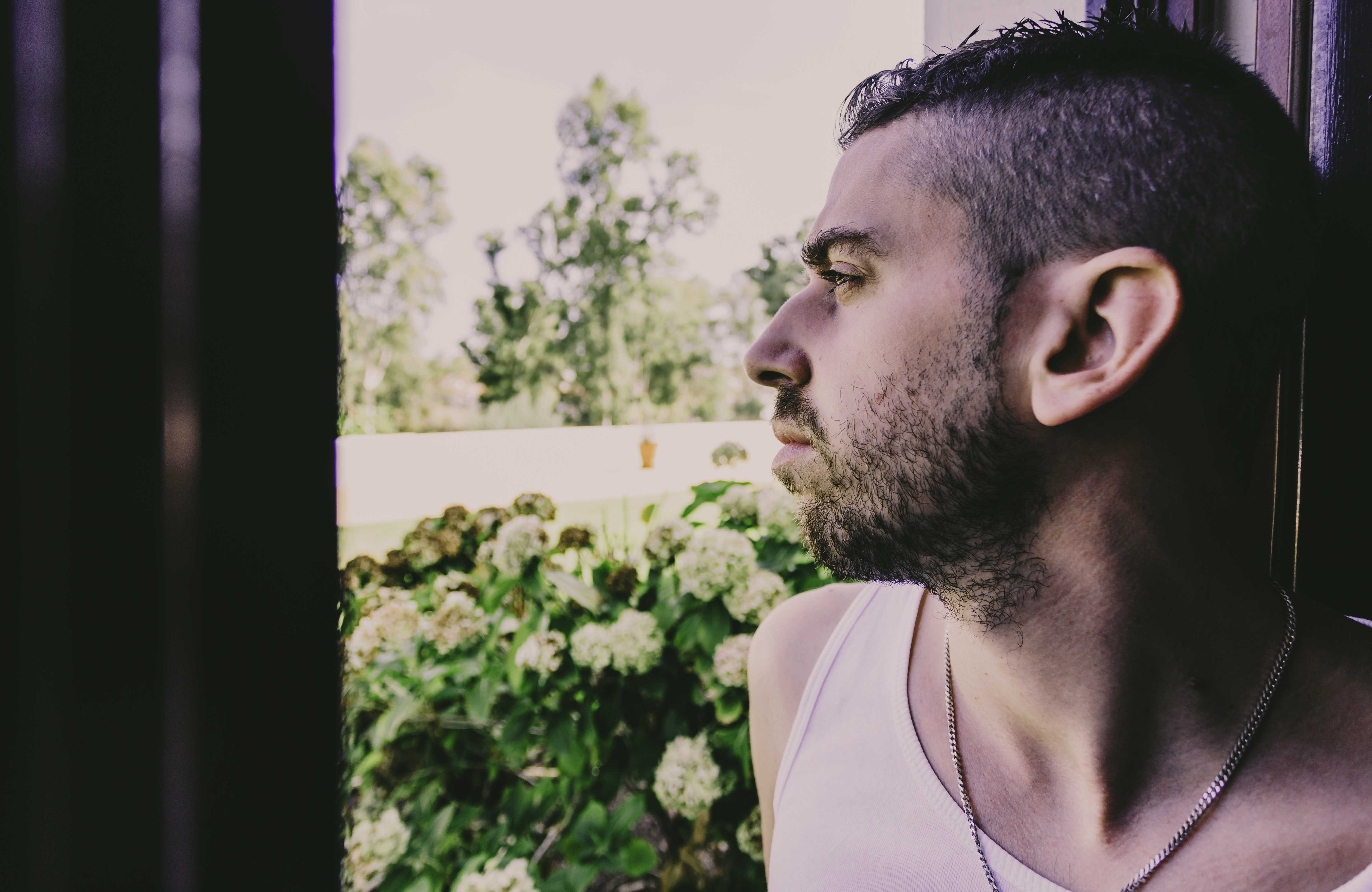 Man dealing with Tranq addiction looking out window.